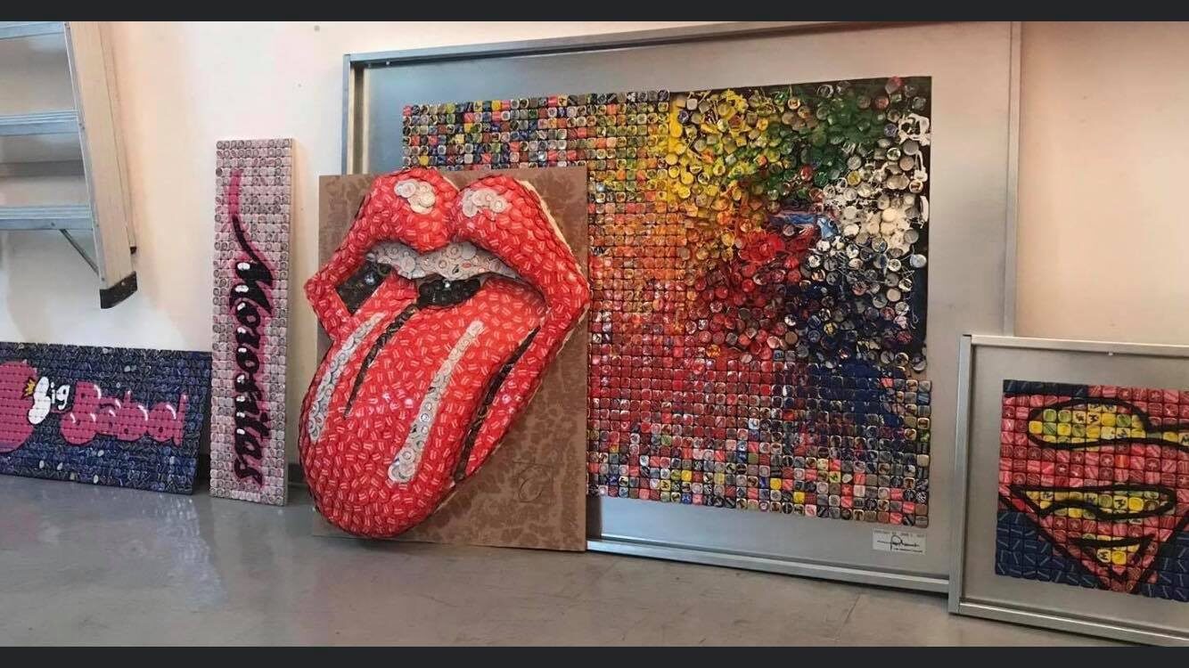 Opere di tappi a corona nello studio di Luigi Masecchia: la lingua dei Rolling Stones, il logo di Superman e un grande mosaico multicolore